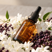 Load image into Gallery viewer, Brown glass dropper bottle with black cap on a bed of white and purple flowers.
